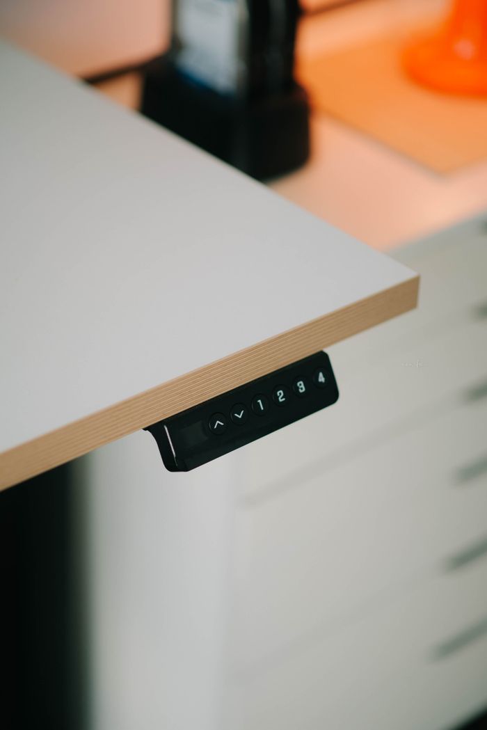 Close-up of a modern adjustable height desk with integrated control panel for height adjustment.